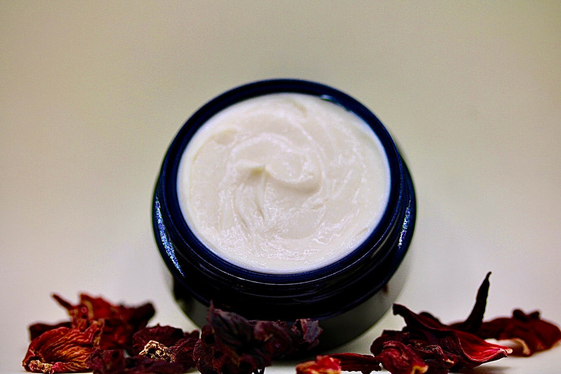 Rose Tulsi Hibiscus plant-based natural facial cream in sustainable jar surrounded by hibiscus tea petals